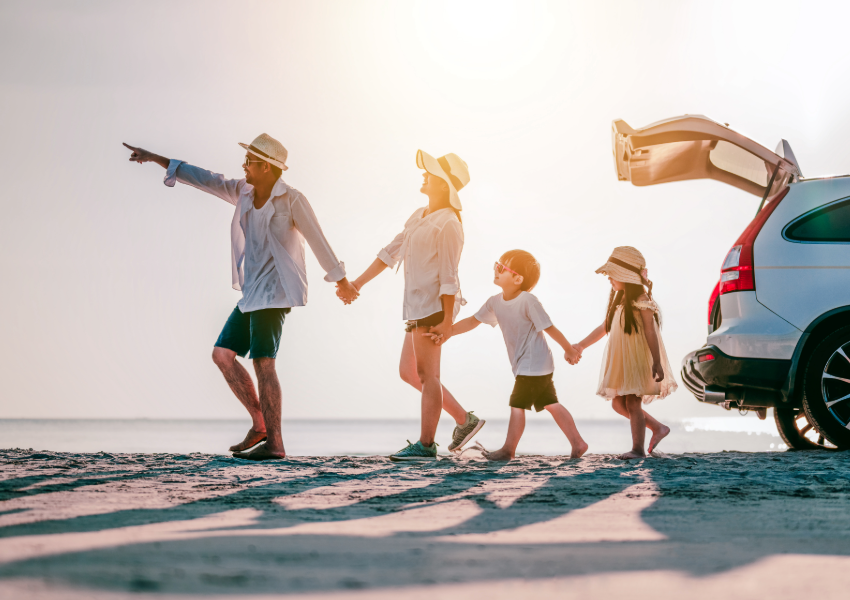 Family pointing towards the horizon on a beach at sunset.